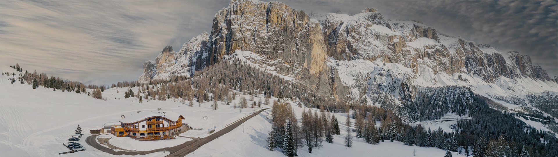 Panoramic aerial view of Chalet Gerard immersed in a vast, snowy winter landscape at the foot of an imposing mountain